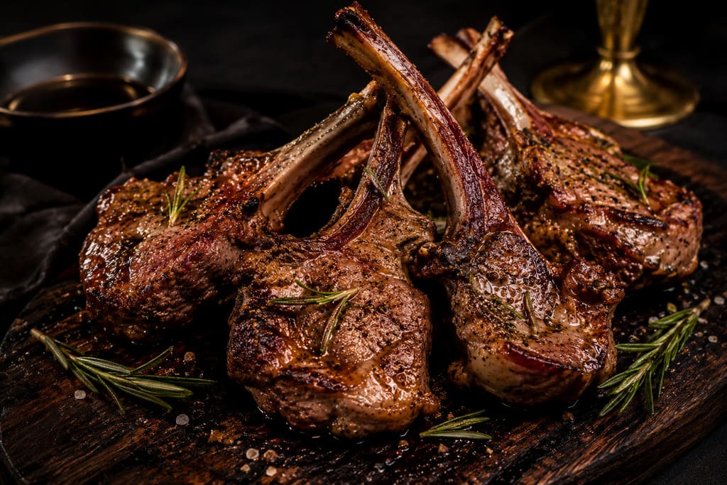 Kosher lamb chops on a dark rustic serving board